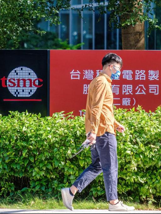 Eine Person mit Coronamaske läuft vor einem Firmengebäude von TSMC (Taiwan Semiconductor Manufacturing Company) in Hsinchu, Taiwan, entlang.