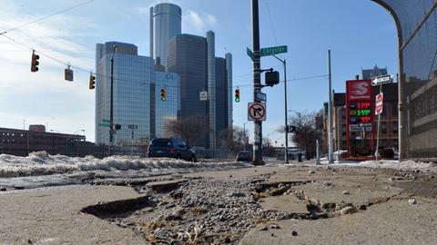 Sanierungsbedarf an allen Ecken: Die einst floriende Auto-Industriestadt Detroit steht kurz vor der Pleite. Aufgerissene Straße, im Hintergrund Hochhäuser.