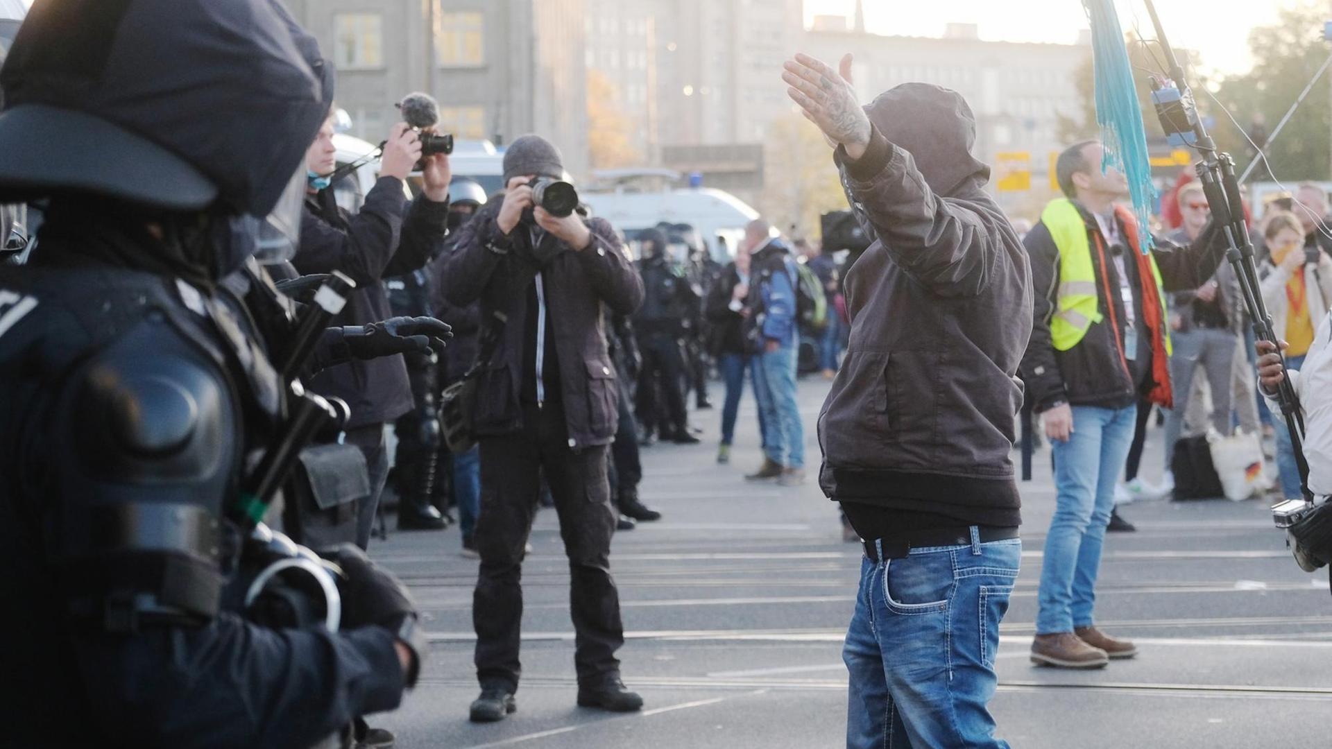 07.11.2020, Sachsen, Leipzig: Teilnehmer der Demonstration der Initiative ?Querdenken? rufen und gestikulieren mit ausgebreiteten Armen auf dem Augustusplatz vor Medienvertretern und Polizisten. An der Kundgebung gegen die von Bund und Ländern beschlossenen Corona-Maßnahmen nehmen mehrere Tausend Menschen teil. Foto: Sebastian Willnow/dpa-Zentralbild/dpa | Verwendung weltweit 07.11.2020, Sachsen, Leipzig: Teilnehmer der Demonstration der Initiative ?Querdenken? rufen und gestikulieren mit ausgebreiteten Armen auf dem Augustusplatz vor Medienvertretern und Polizisten. An der Kundgebung gegen die von Bund und Ländern beschlossenen Corona-Maßnahmen nehmen mehrere Tausend Menschen teil. Foto: Sebastian Willnow/dpa-Zentralbild/dpa | Verwendung weltweit