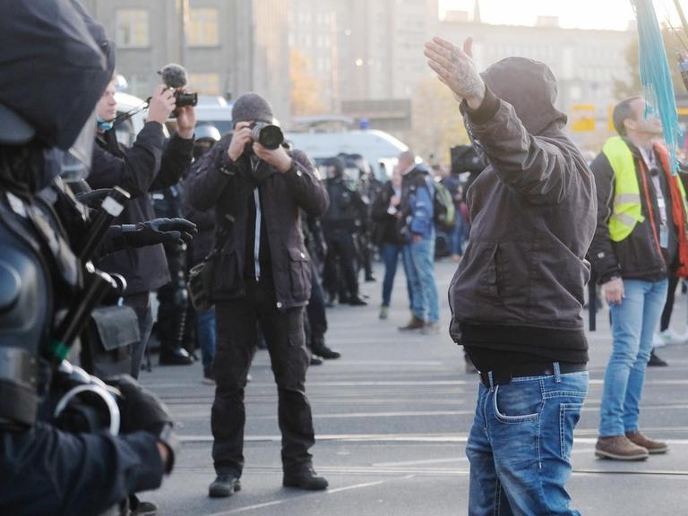 07.11.2020, Sachsen, Leipzig: Teilnehmer der Demonstration der Initiative ?Querdenken? rufen und gestikulieren mit ausgebreiteten Armen auf dem Augustusplatz vor Medienvertretern und Polizisten. An der Kundgebung gegen die von Bund und Ländern beschlossenen Corona-Maßnahmen nehmen mehrere Tausend Menschen teil. Foto: Sebastian Willnow/dpa-Zentralbild/dpa | Verwendung weltweit