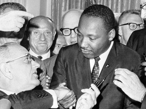 Nach der Unterzeichnung des Bürgerrechts-Gesetzes am 2.7.1964 in Washington DC. reicht US-Präsident Lyndon Baines Johnson (l) den Federhalter an den Bürgerrechtler Martin Luther King weiter und gibt ihm die Hand. Das Bürgerrechtsgesetz sollte eine Gleichberechtigung der farbigen Bevölkerung in den Vereinigten Staaten von Amerika garantieren und galt als eine der wichtigsten Gesetzes-Entscheidungen in der Geschichte der USA. King wurde am 4.4.1968 im Alter von 39 Jahren in Memphis von James Earl Ray erschossen.