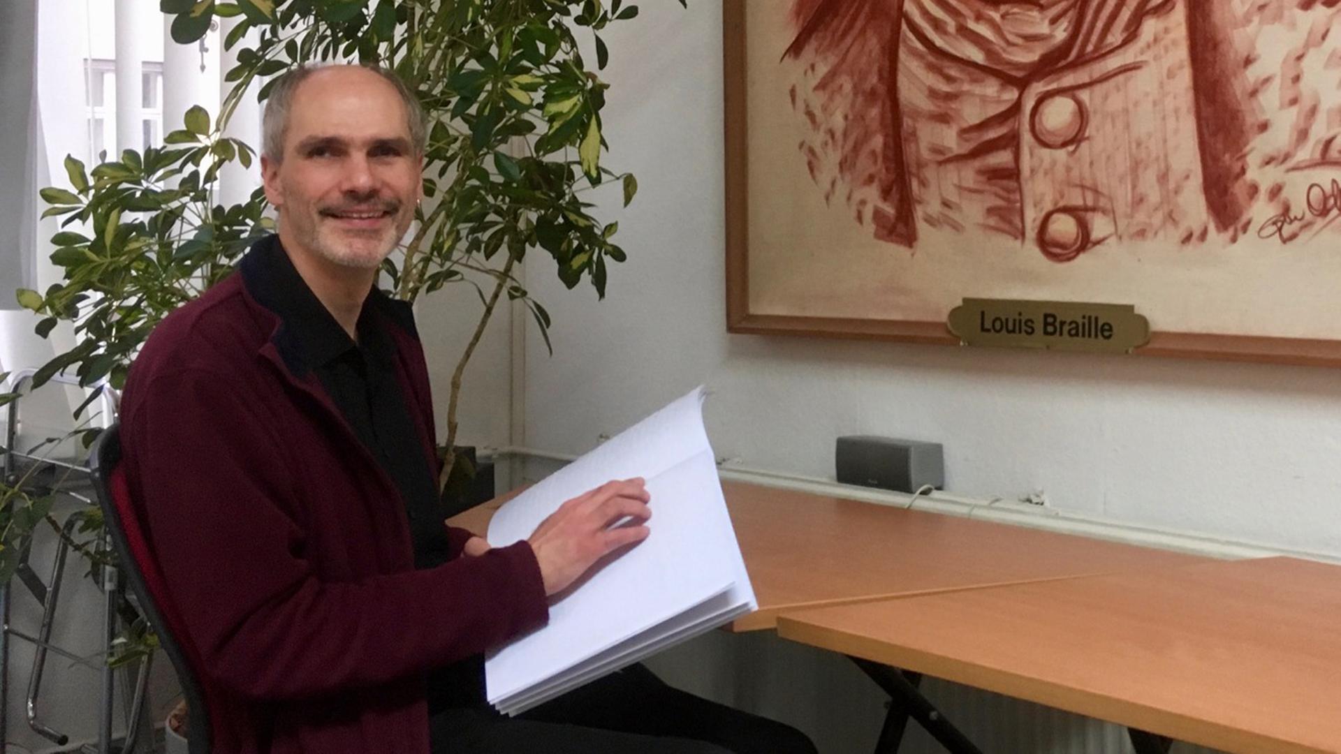 Reiner Delgado, Sozialreferent beim Deutschen Blinden- und Sehbehindertenverband, mit einer Ausgabe der Tagesnachrichten für Taubblinde Reiner Delgado, Sozialreferent beim Deutschen Blinden- und Sehbehindertenverband, mit einer Ausgabe der Tagesnachrichten für Taubblinde