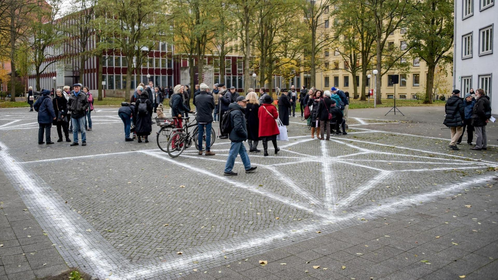 09.11.2018, Hamburg: Besucher einer Mahnwache stehen auf dem Joseph-Carlebach-Platz, auf dem mit Kreide die Grundrisse der Bornplatz-Synagoge, die von den Nationalsozialisten zerstört wurde, aufgemalt sind. Zum Gedenken an die Pogromnacht von 1938 fand auf dem Platz eine Mahnwache statt. 09.11.2018, Hamburg: Besucher einer Mahnwache stehen auf dem Joseph-Carlebach-Platz, auf dem mit Kreide die Grundrisse der Bornplatz-Synagoge, die von den Nationalsozialisten zerstört wurde, aufgemalt sind. Zum Gedenken an die Pogromnacht von 1938 fand auf dem Platz eine Mahnwache statt.