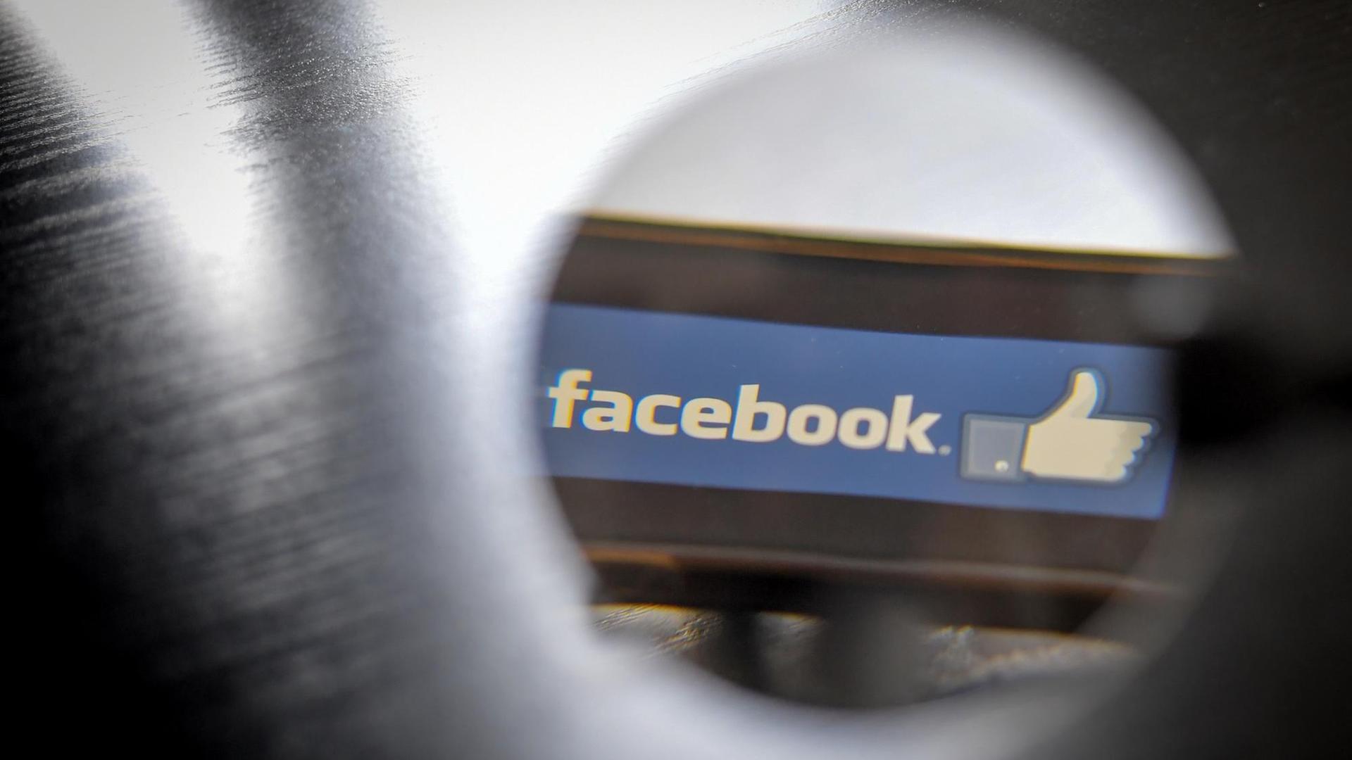 Symboldbild. Ein Facebook-Logo auf einem Smartphone durch ein Loch fotografiert. Symboldbild. Ein Facebook-Logo auf einem Smartphone durch ein Loch fotografiert.