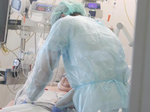 Ein Pfleger überwacht die Monitore bei einem Patienten auf einer Covid 19 Intensivstation.