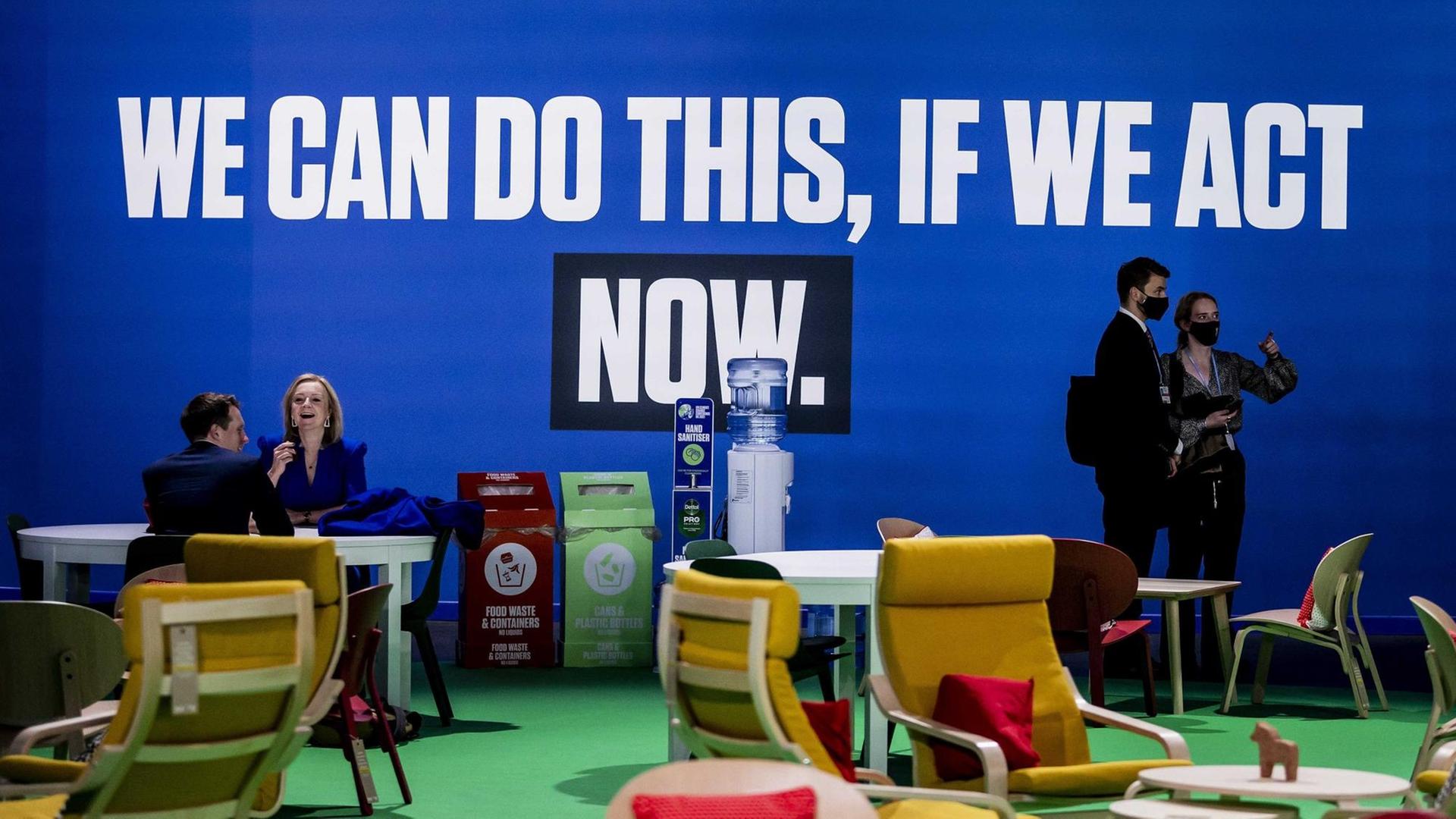 "We can do this if we act now" steht auf einem Transparent, das an einer blauen Wand hängt. "We can do this if we act now" steht auf einem Transparent, das an einer blauen Wand hängt.