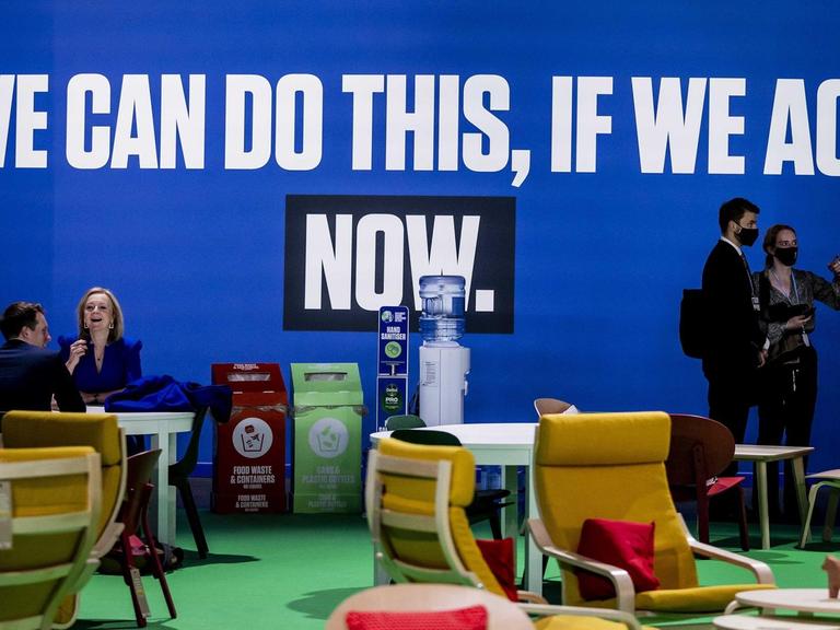 "We can do this if we act now" steht auf einem Transparent, das an einer blauen Wand hängt.