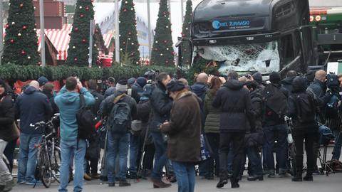 Schaulustige und Journalisten stehen am 20.12.2016 in Berlin vor einem beschädigten LKW. Bei einem möglichen Anschlag war ein Unbekannter am Montag (19.12.) mit einem Lastwagen auf einen Weihnachtsmarkt an der Gedächtniskirche gefahren.