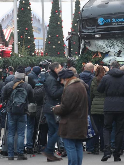 Schaulustige und Journalisten stehen am 20.12.2016 in Berlin vor einem beschädigten LKW. Bei einem möglichen Anschlag war ein Unbekannter am Montag (19.12.) mit einem Lastwagen auf einen Weihnachtsmarkt an der Gedächtniskirche gefahren.