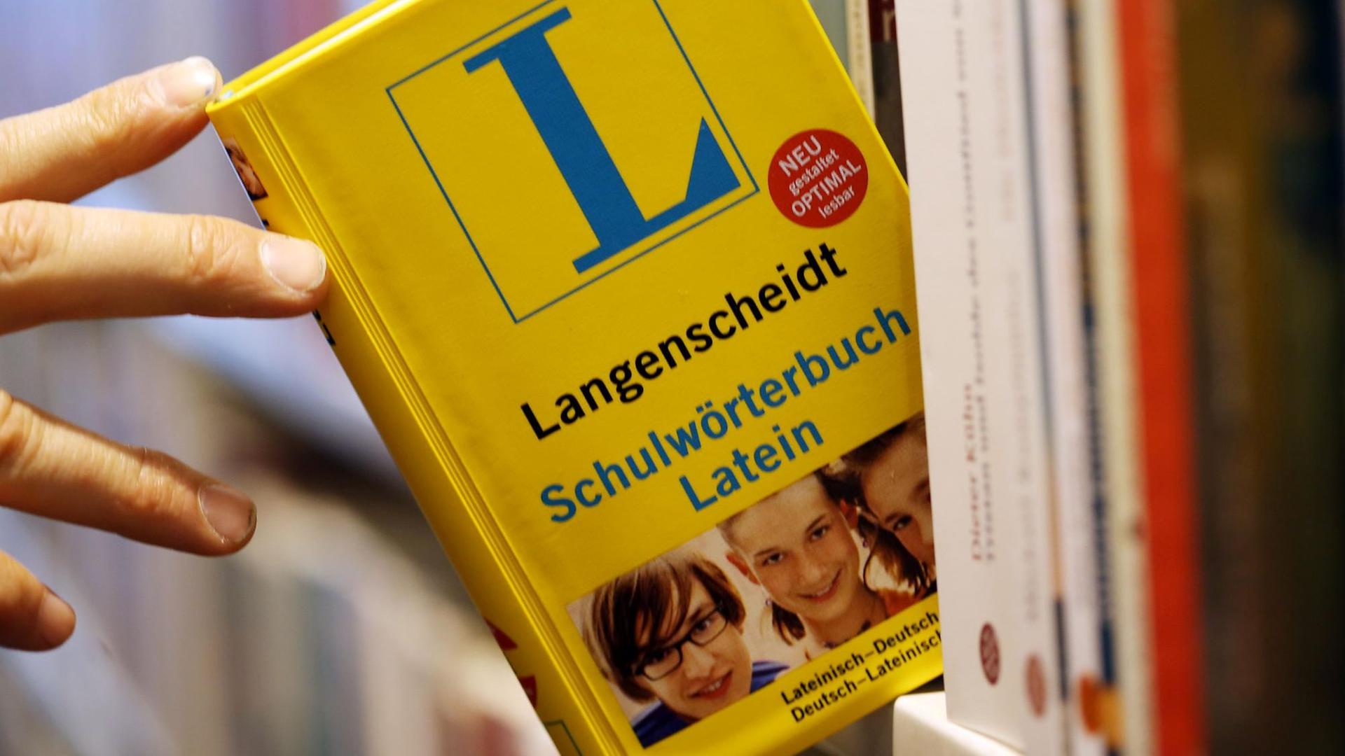 Ein lateinisches Wörterbuch wird am 03.04.2013 in einer Buchhandlung in Köln (Nordrhein-Westfalen) aus einem Regal genommen. Nordrhein-Westfalens SPD und Grüne wollen die Latinums-Pflicht für Lehramtsstudenten auf den Prüfstand stellen. Ein lateinisches Wörterbuch wird am 03.04.2013 in einer Buchhandlung in Köln (Nordrhein-Westfalen) aus einem Regal genommen. Nordrhein-Westfalens SPD und Grüne wollen die Latinums-Pflicht für Lehramtsstudenten auf den Prüfstand stellen.