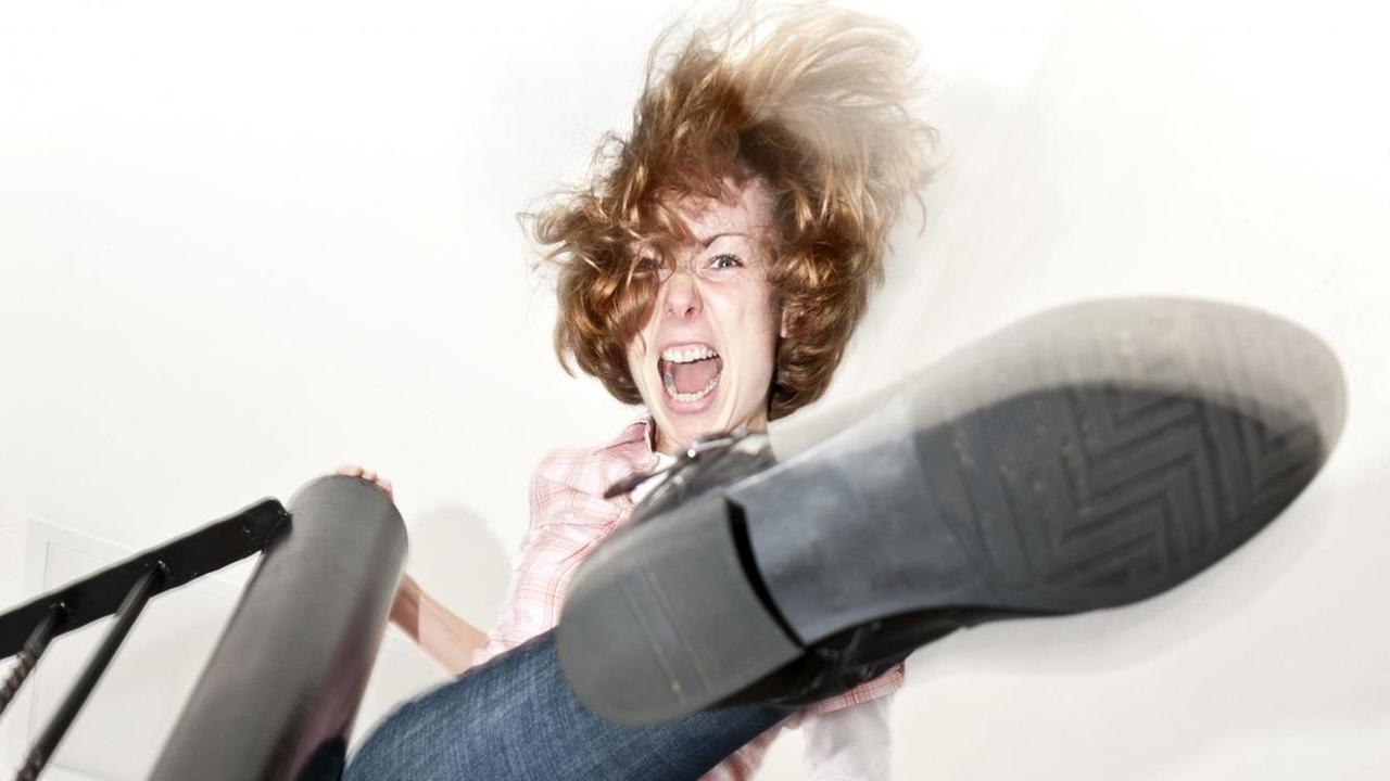 Eine junge Frau auf einer Treppe tritt wütend nach unten. Eine junge Frau auf einer Treppe tritt wütend nach unten.
