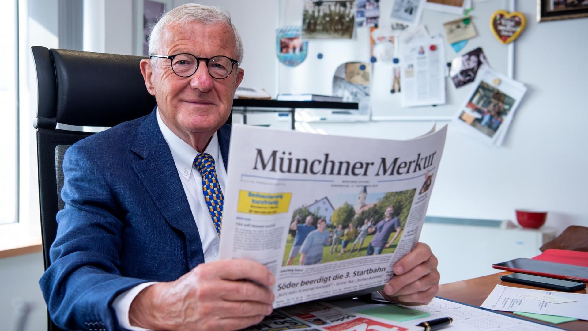 Zeitungsverleger, hält eine Tageszeitung in seinem Büro in seinen Händen. Zeitungsverleger, hält eine Tageszeitung in seinem Büro in seinen Händen.