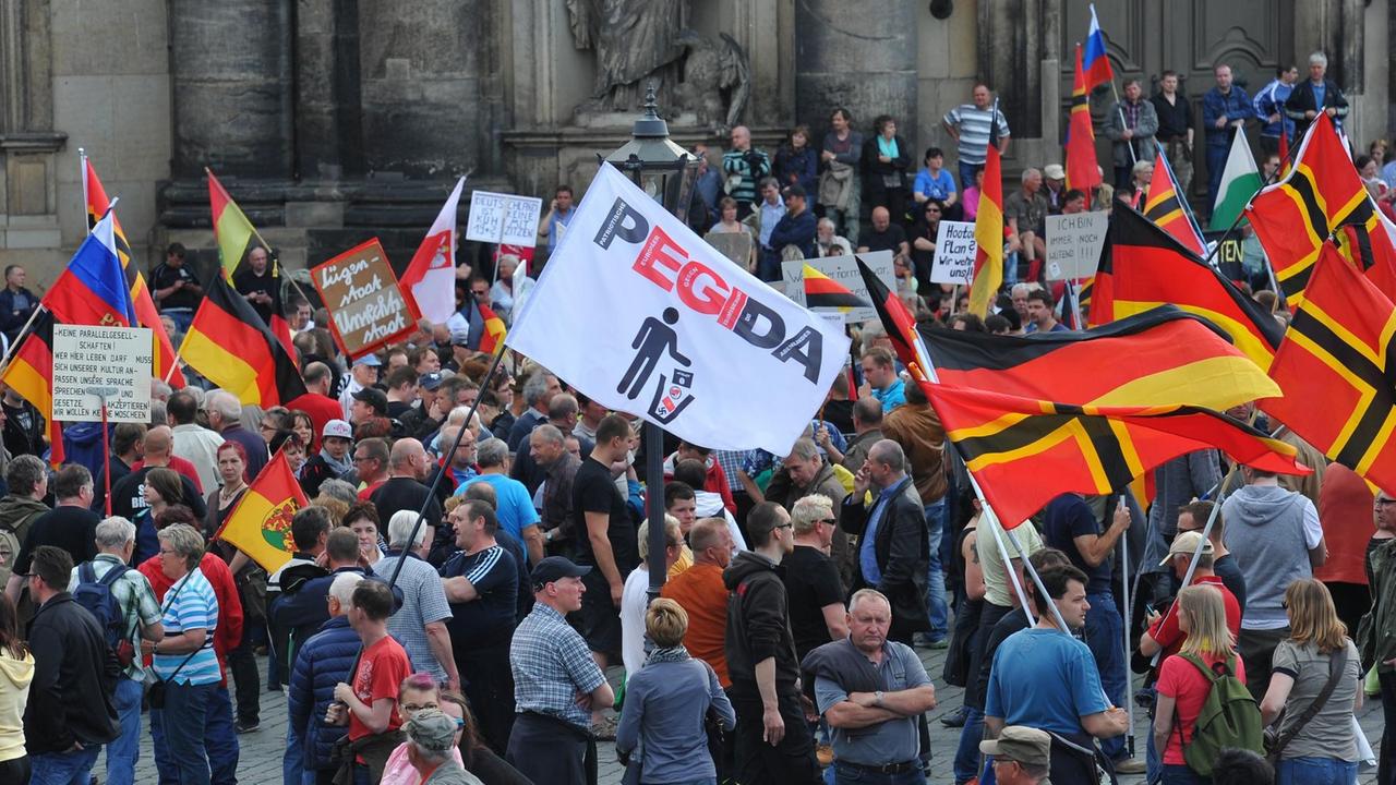 Einige hundert Anhänger des islamkritischen Bündnisses Pegida treffen sich am 04.05.2015 in Dresden (Sachsen) zu einer Kundgebung und halten Deutschland-Fahnen hoch. Einige hundert Anhänger des islamkritischen Bündnisses Pegida treffen sich am 04.05.2015 in Dresden (Sachsen) zu einer Kundgebung und halten Deutschland-Fahnen hoch.