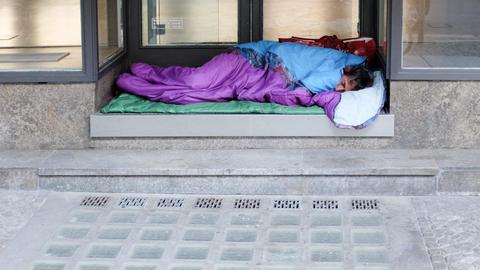 In einem Hauseingang in Berlin schläft ein Obdachloser in einem Schlafsack.