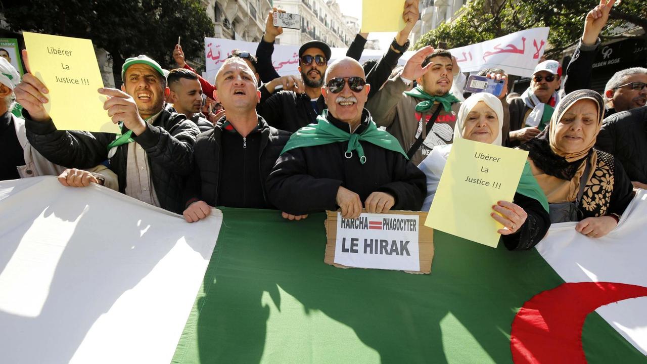 Demonstranten hinter einer großen Algerien-Flagge