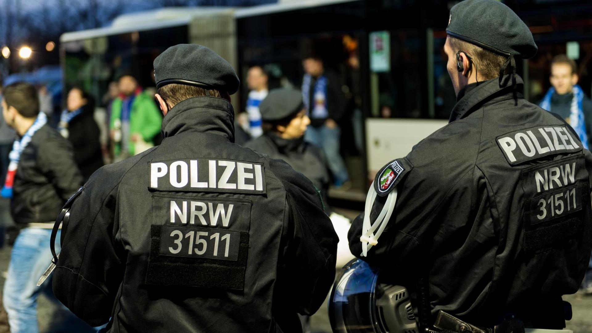 Zwei Polizeibeamten überwachen die Ankunft von Bussen mit Fußballfans vor dem Spiel zwischen Fortuna Düsseldorf und dem MSV Duisburg in der ESPRIT-Arena in Düsseldorf am 20.11.2015. Zwei Polizeibeamten überwachen die Ankunft von Bussen mit Fußballfans vor dem Spiel zwischen Fortuna Düsseldorf und dem MSV Duisburg in der ESPRIT-Arena in Düsseldorf am 20.11.2015.