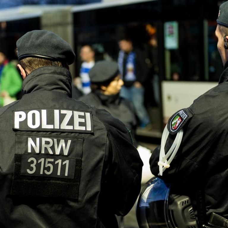 Zwei Polizeibeamten überwachen die Ankunft von Bussen mit Fußballfans vor dem Spiel zwischen Fortuna Düsseldorf und dem MSV Duisburg in der ESPRIT-Arena in Düsseldorf am 20.11.2015.
