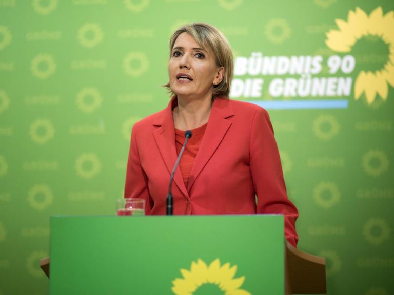 Simone Peter spricht bei einer Pressekonferenz, im Hintergrund das Parteilogo der Grünen.