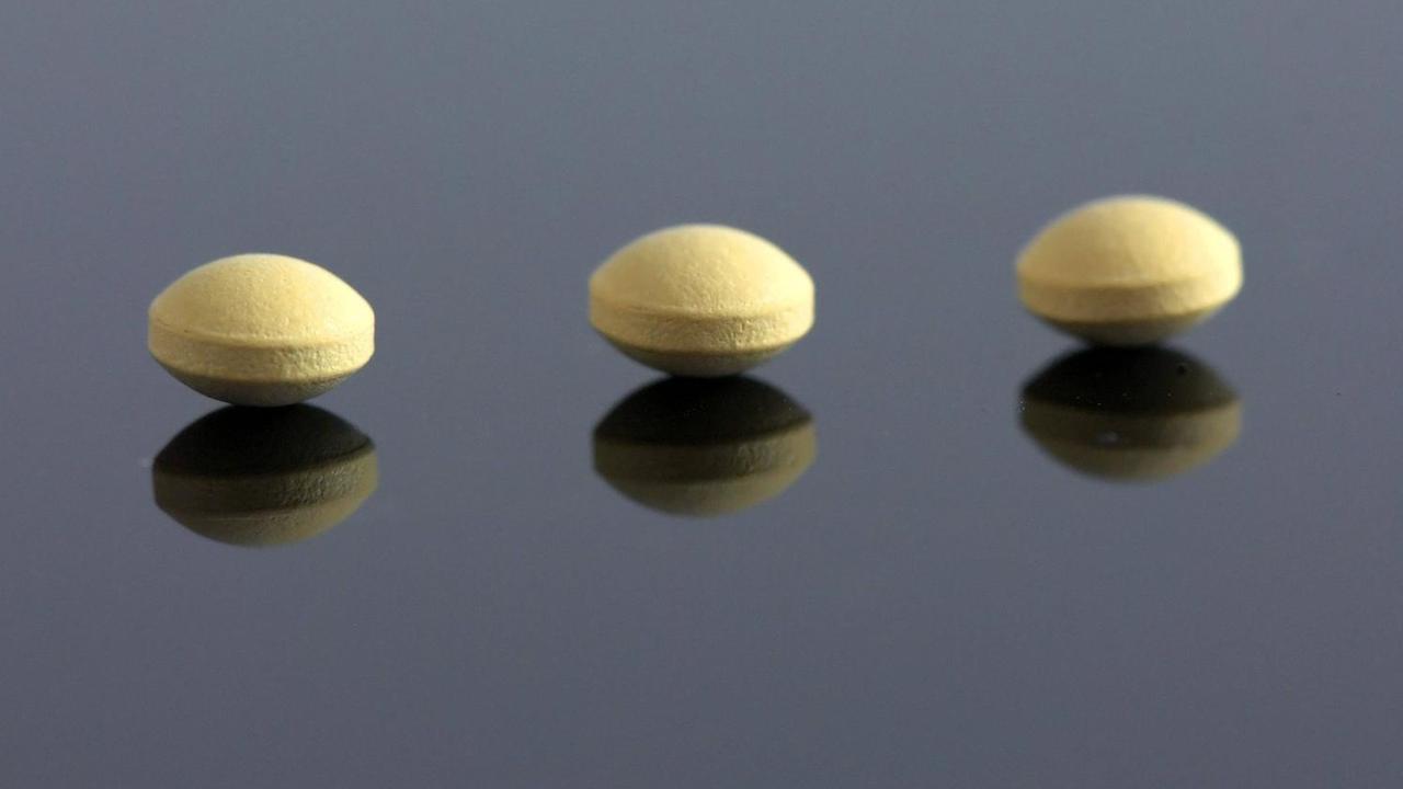Drei Anti-Baby-Pillen auf einer spiegelnden Unterlage. Drei Anti-Baby-Pillen auf einer spiegelnden Unterlage.