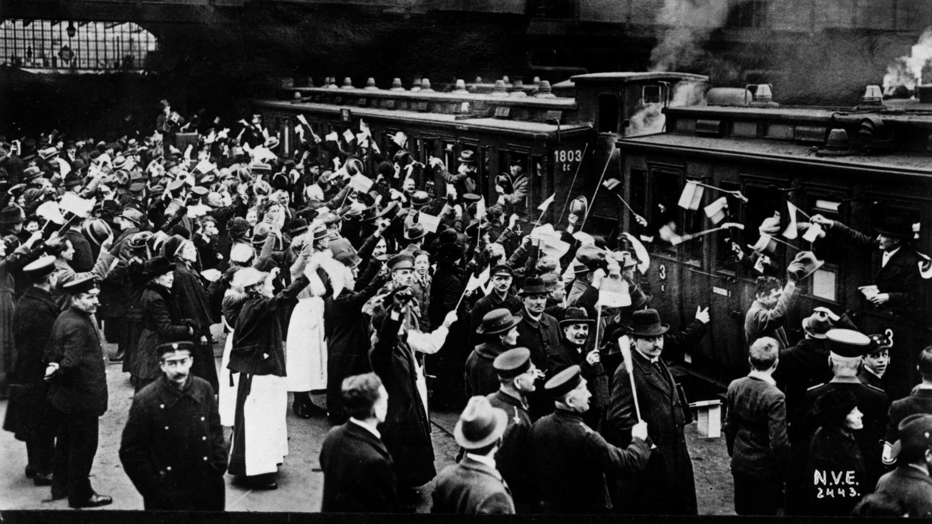 Ein Schwarzweiß-Foto zeigt eine große Menschenmenge am Gleis in einer großen Bahnhofshalle ,zum Großteil Fahnen schwenkend vor einem Zug aus zwei Waggons. Links sind zahlreiche Frauen in weißen Röcken, vermutlich einer Tracht zu sehen die dem Zug entgegen winken. Auf der rechten Bildhälfte bfinden sich zahlreiche Männer in Anzug und mit Schirmmützen Ein Sonderzug für Stimmberechtigte bei der Volksabstimmung Schlesien am 20. Maäz 1921 wartet im Schlesischen Bahnhof Berlin Ein Schwarzweiß-Foto zeigt eine große Menschenmenge am Gleis in einer großen Bahnhofshalle ,zum Großteil Fahnen schwenkend vor einem Zug aus zwei Waggons. Links sind zahlreiche Frauen in weißen Röcken, vermutlich einer Tracht zu sehen die dem Zug entgegen winken. Auf der rechten Bildhälfte bfinden sich zahlreiche Männer in Anzug und mit Schirmmützen Ein Sonderzug für Stimmberechtigte bei der Volksabstimmung Schlesien am 20. Maäz 1921 wartet im Schlesischen Bahnhof Berlin