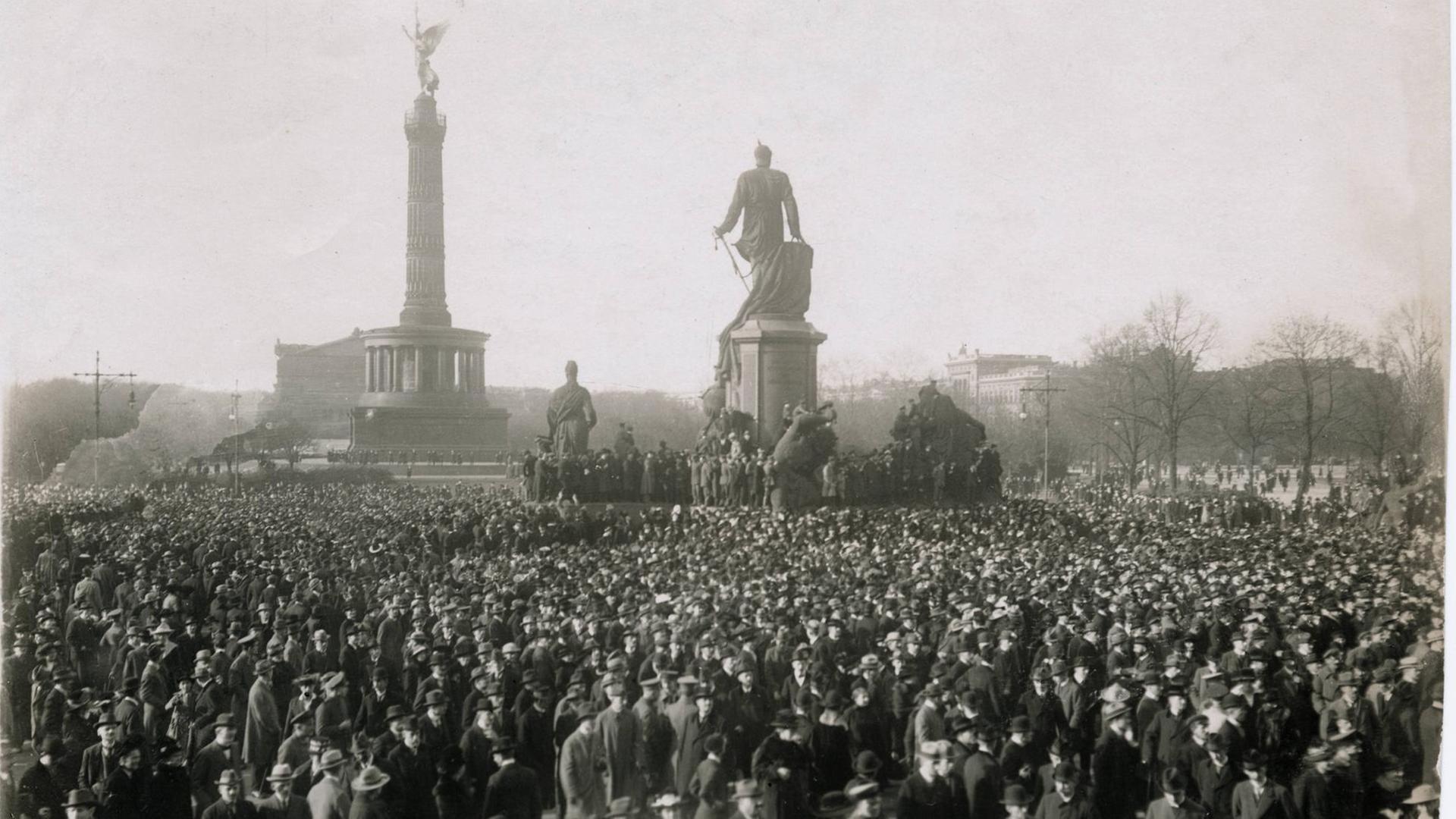 Eine Massenkundgebung auf dem Berliner Königsplatz am 10. November 1918. In der Bildmitte ist das Bismarckdenkmal zu sehen, im Hintergrund Siegessäule und Krolloper.