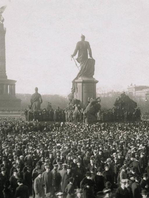 Eine Massenkundgebung auf dem Berliner Königsplatz am 10. November 1918. In der Bildmitte ist das Bismarckdenkmal zu sehen, im Hintergrund Siegessäule und Krolloper.
