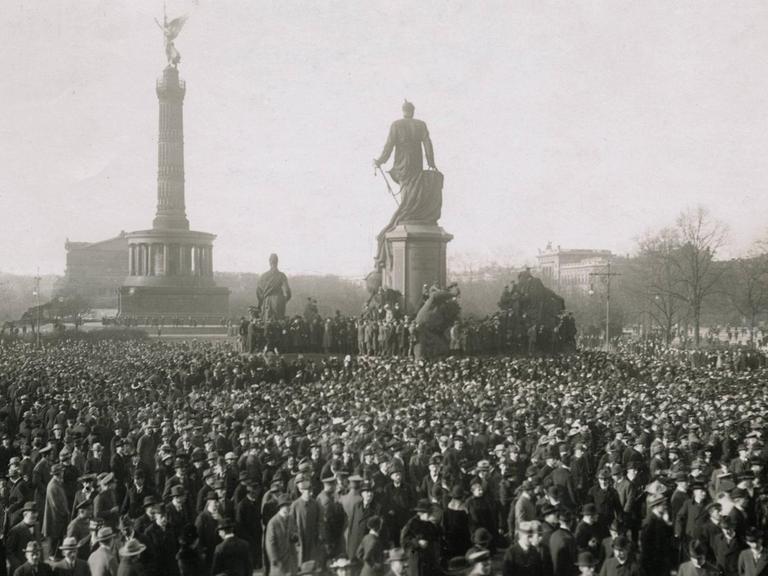Eine Massenkundgebung auf dem Berliner Königsplatz am 10. November 1918. In der Bildmitte ist das Bismarckdenkmal zu sehen, im Hintergrund Siegessäule und Krolloper.