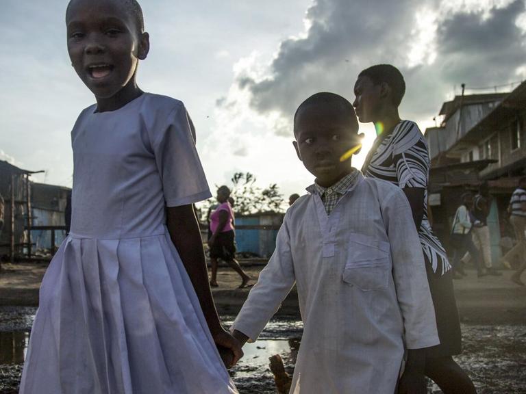 Kinder laufen über eine aufgeweichte Straße im Slum von Mathare in Nairobi /Kenia
