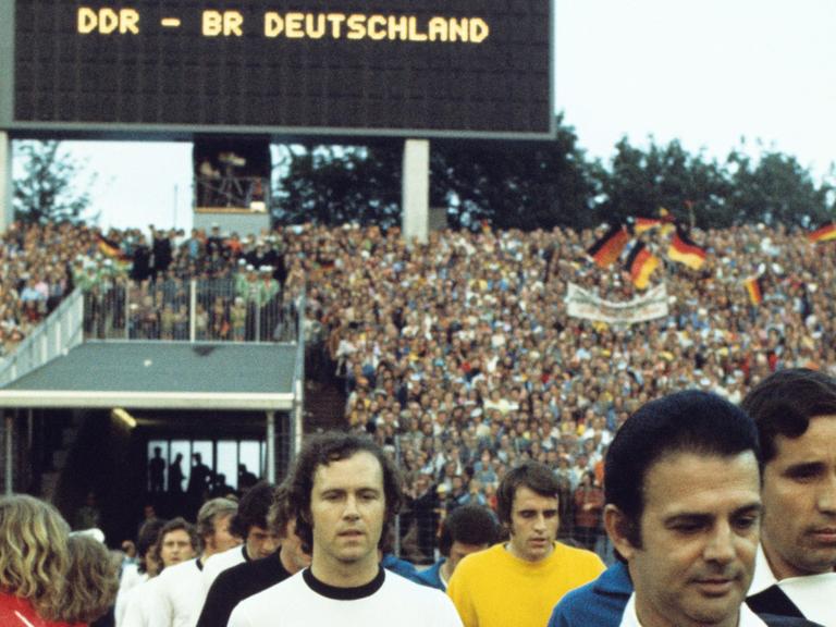Der Kapitän der deutschen Fußball-Nationalmannschaft, Franz Beckenbauer, beim Einzug in des Volksparkstadion in Hamburg am 22.06.1974. Die bundesdeutsche Elf verlor in der Vorrunde der Fußball-Weltmeisterschaft das Spiel gegen die DDR überraschend mit 0:1 Toren. Torschütze war Jürgen Sparwasser. Ganz rechts der Schiedsrichter Ramon Bareto Ruiz (Uruguay).