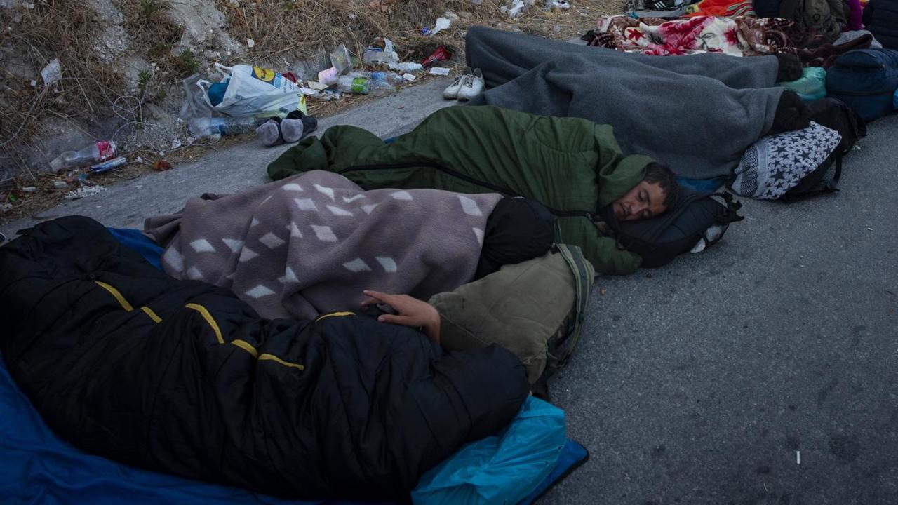 Nach einem Brand im Lager Moria auf der Insel Lesbos schlafen Flüchtlinge obdachlos am Straßenrand. Nach einem Brand im Lager Moria auf der Insel Lesbos schlafen Flüchtlinge obdachlos am Straßenrand.