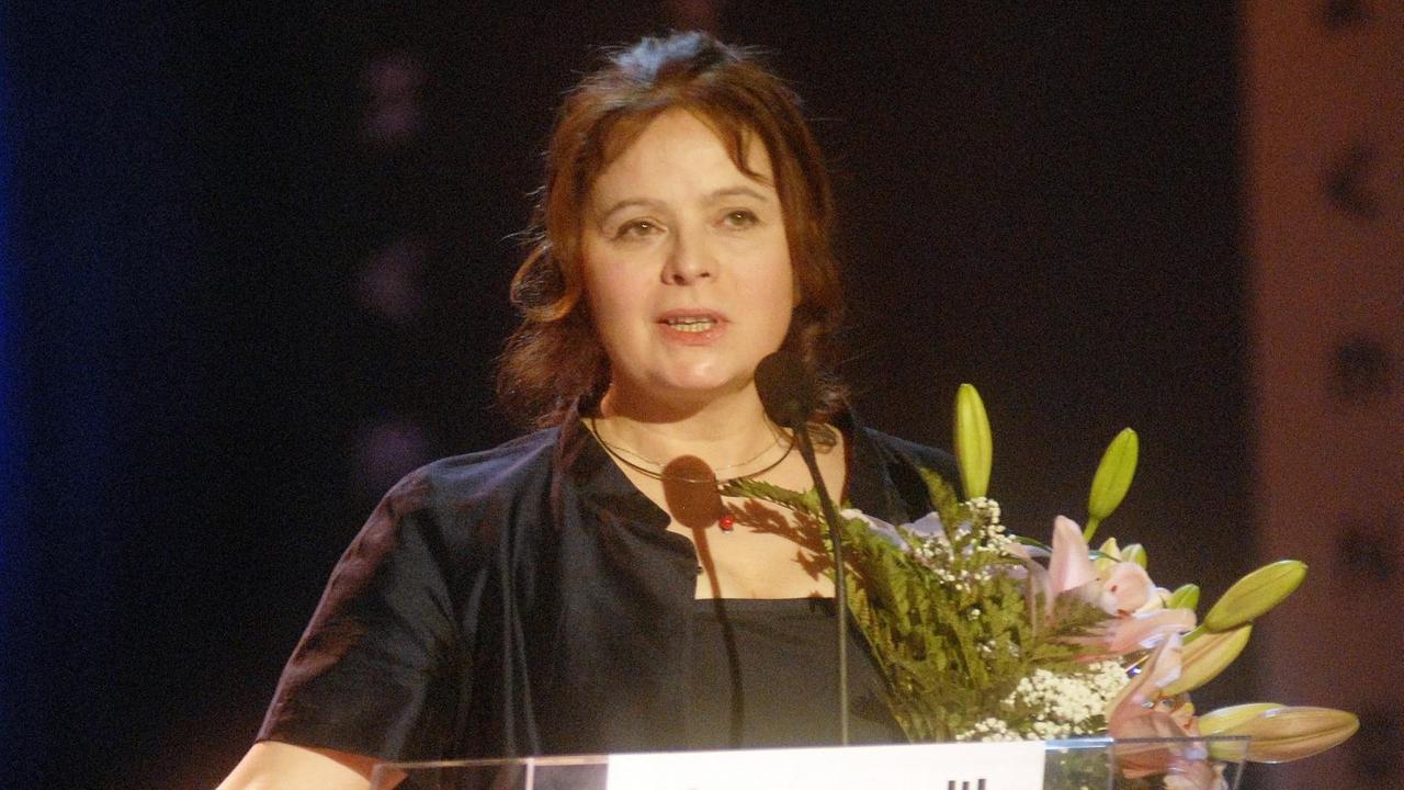 Die tschechische Schauspielerin Libuse Safrankova steht an einem Rednerpult und hält Blumen im Arm.