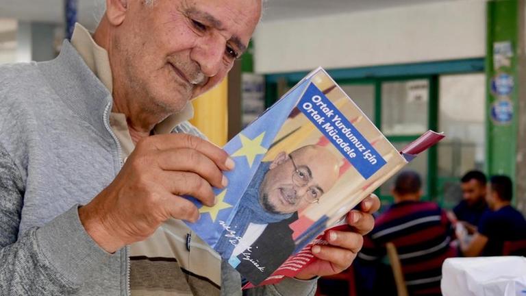 Die Nordzyprer wählen bisher kaum bei der EU-Wahl - das soll sich mit dem Kandidaten Niyazi Kızılyürek ändern. Ein älterer Mann aus dem Norden Zyperns schaut sich eine Wahlwerbung an.
