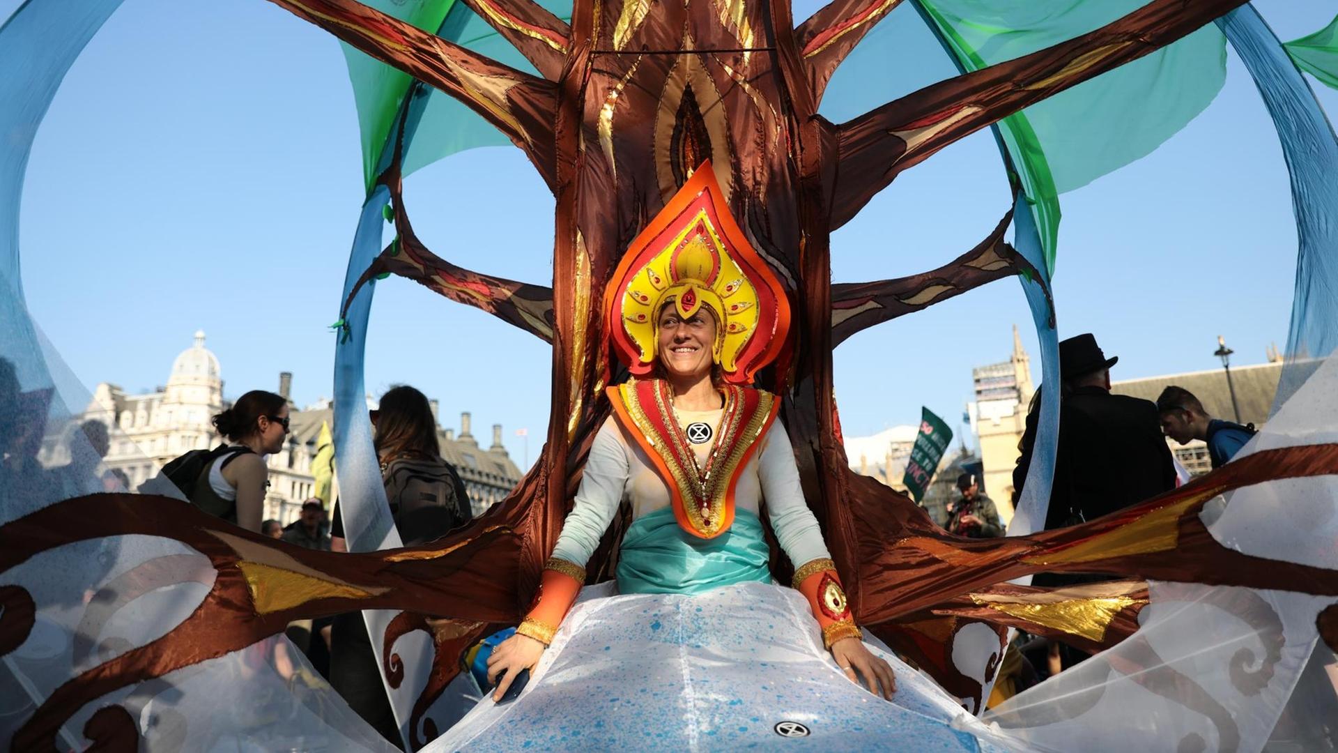 Eine Aktivistin von Extinction Rebellion steht als Baum verkleidet auf dem Parliament Square in Westminster, London bei einer Demonstration am 21. April 2019 in London. Eine Aktivistin von Extinction Rebellion steht als Baum verkleidet auf dem Parliament Square in Westminster, London bei einer Demonstration am 21. April 2019 in London.