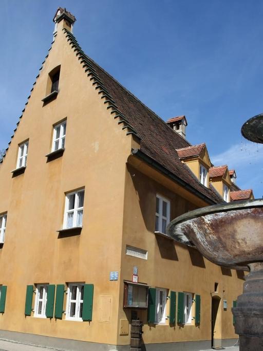 Ein Brunnen vor den alten Wohnhäusern der Fuggerei in Augsburg. Mit der Fuggerei hat sich Finanzgenie Jakob Fugger im 16. Jahrhundert ein Denkmal gesetzt.