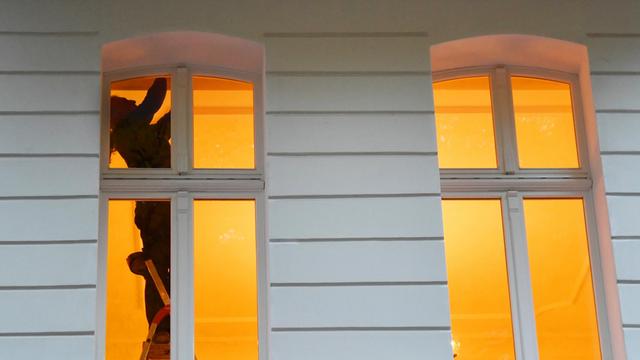 Ein Mann steht am 02.11.2016 in Berlin an einem Fenster in einer Wohnung auf einer Leiter. Foto: Jens Kalaene/dpa | Verwendung weltweit