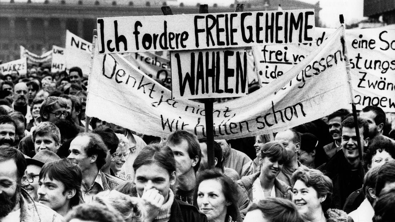 Demonstration für Reformen in der DDR am 4.11.1989 in Ost-Berlin. Menschen halten ein Banner, auf dem "Ich fordere freie geheime Wahlen" steht. Demonstration für Reformen in der DDR am 4.11.1989 in Ost-Berlin. Menschen halten ein Banner, auf dem "Ich fordere freie geheime Wahlen" steht.