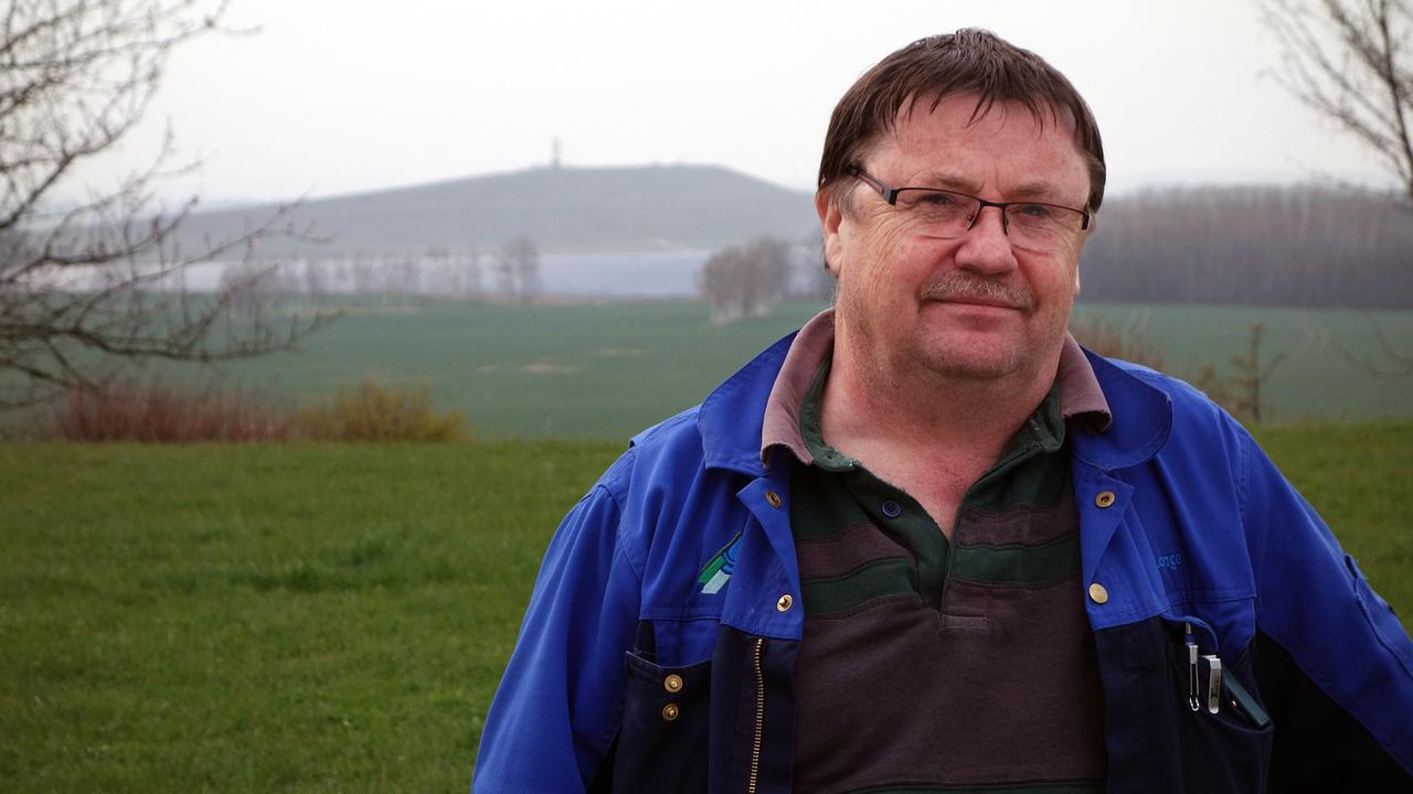 Frank Lange vom Kirchlichen Umweltverein Ronneburg, im Hintergrund eine Halde der Wismut