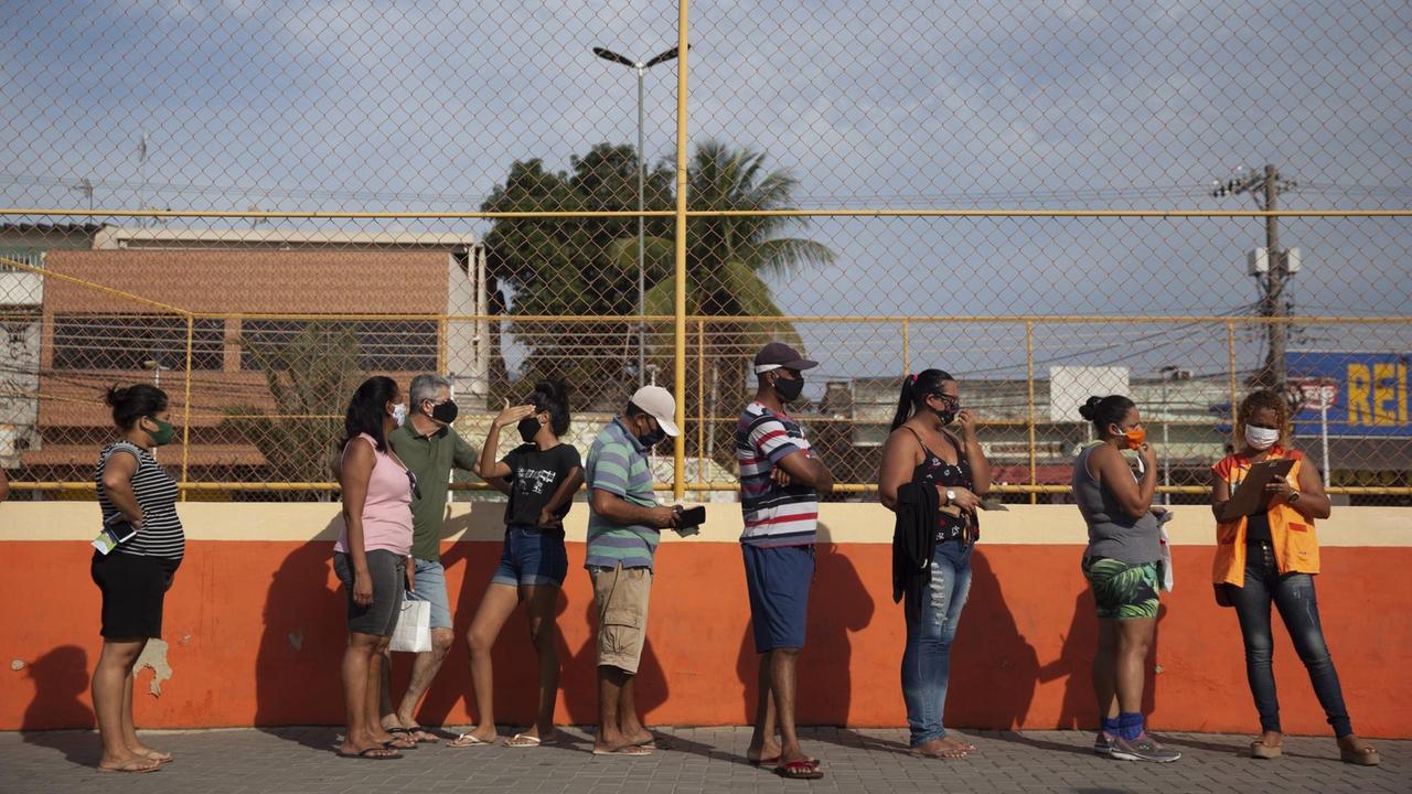 Menschen stehen in Rio de Janeiro in einer Schlange an.