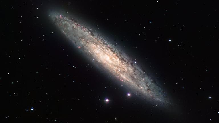 Measuring 70 000 light-years across and laying 13 million light-years away, the nearly edge-on spiral galaxy NGC 253 is revealed here in an image from the Wide Field Imager (WFI) on the MPG/ESO 2.2-metre telescope at the La Silla Observatory. The image is based on data obtained through four different filters (R, V, H-alpha and OIII). North is up and East to the left. The field of view is 30 arcminutes. Measuring 70 000 light-years across and laying 13 million light-years away, the nearly edge-on spiral galaxy NGC 253 is revealed here in an image from the Wide Field Imager (WFI) on the MPG/ESO 2.2-metre telescope at the La Silla Observatory. The image is based on data obtained through four different filters (R, V, H-alpha and OIII). North is up and East to the left. The field of view is 30 arcminutes.