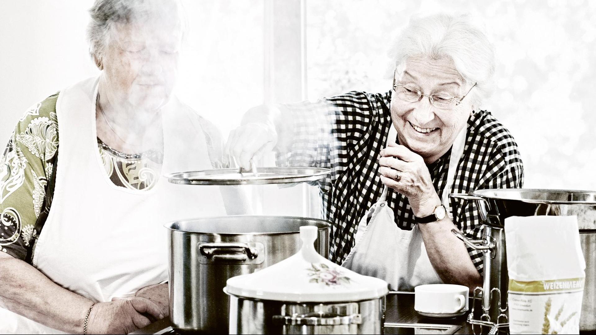 Zwei ältere Frauen stehen in einer hellen Küche und kochen fröhlich. Zwei ältere Frauen stehen in einer hellen Küche und kochen fröhlich.