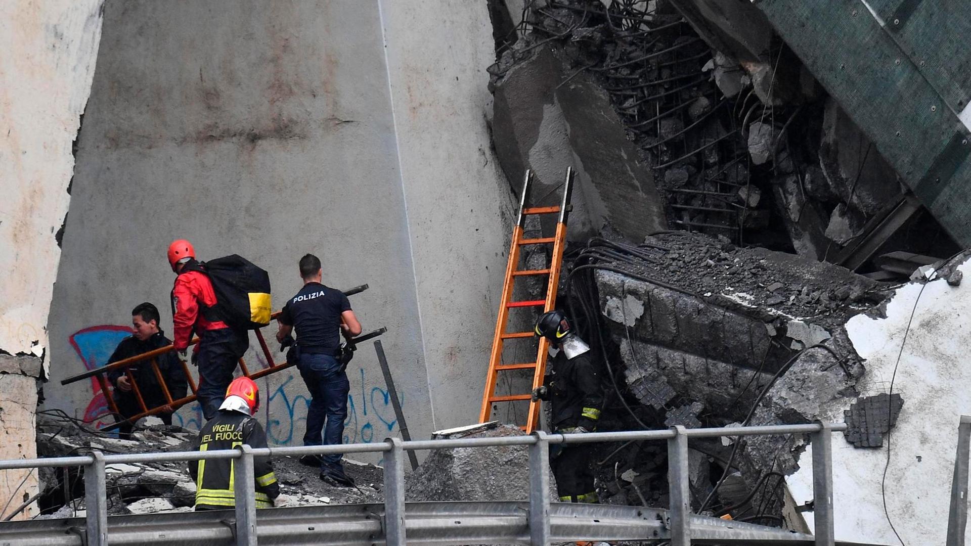 Rettungsarbeiten unter den Trümmern der eingestürzten Morandi Autobahnbrücke.