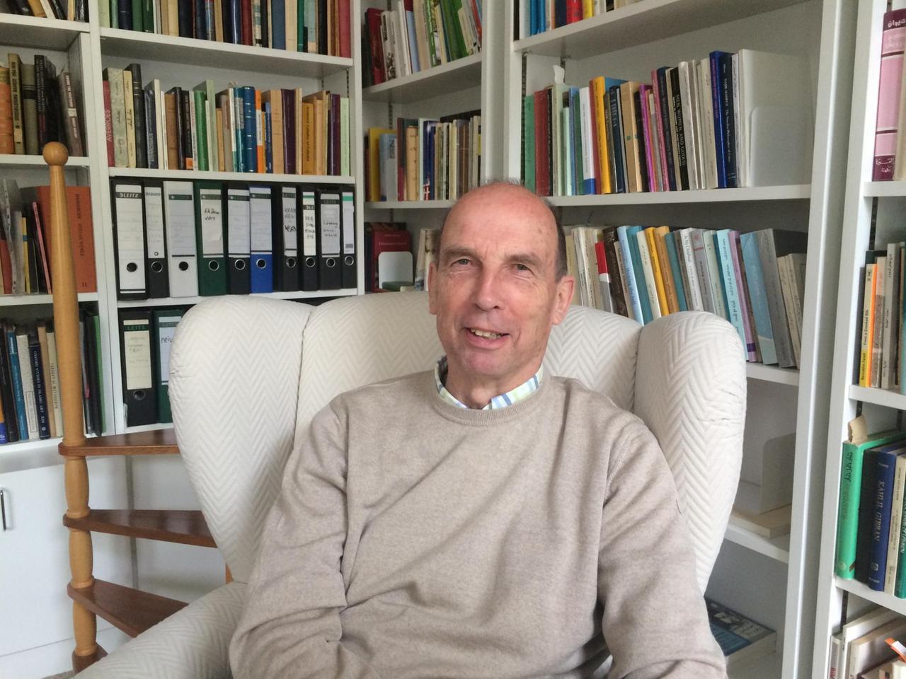 Stefan Wild sitzt in einem Sessel vor Bücherregalen. Stefan Wild sitzt in einem Sessel vor Bücherregalen.