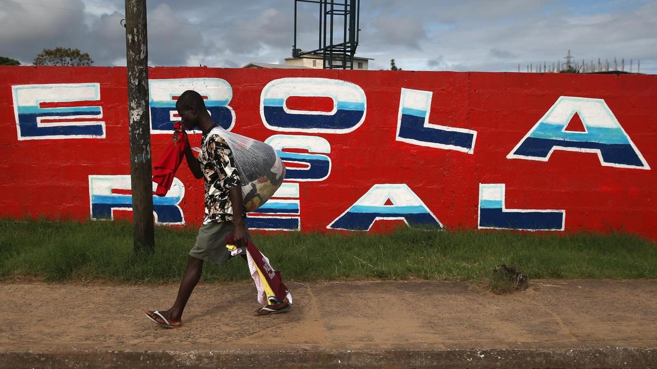 Ein Mann geht an einer Wand vorbei auf der "Ebola is real" geschrieben steht. Ein Mann geht an einer Wand vorbei auf der "Ebola is real" geschrieben steht.