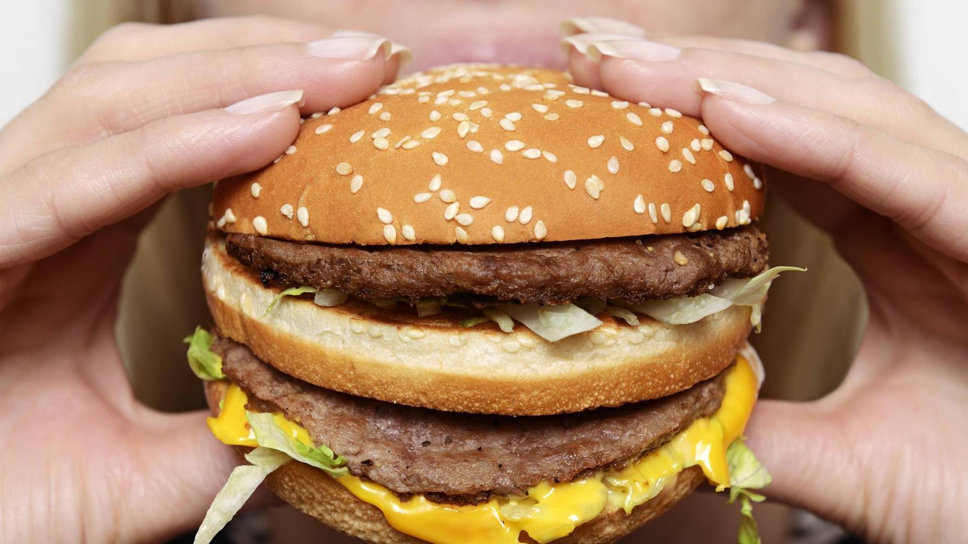 Eine Frau beißt in einen Cheeseburger. Eine Frau beißt in einen Cheeseburger.