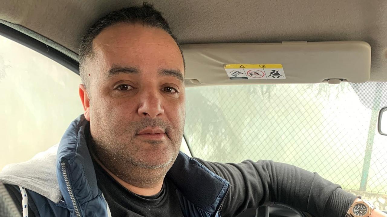 Ein junger Mann in Jeans und Weste dreht sich am Steuer seines Autos sitzend nach hinten um. Ein junger Mann in Jeans und Weste dreht sich am Steuer seines Autos sitzend nach hinten um.