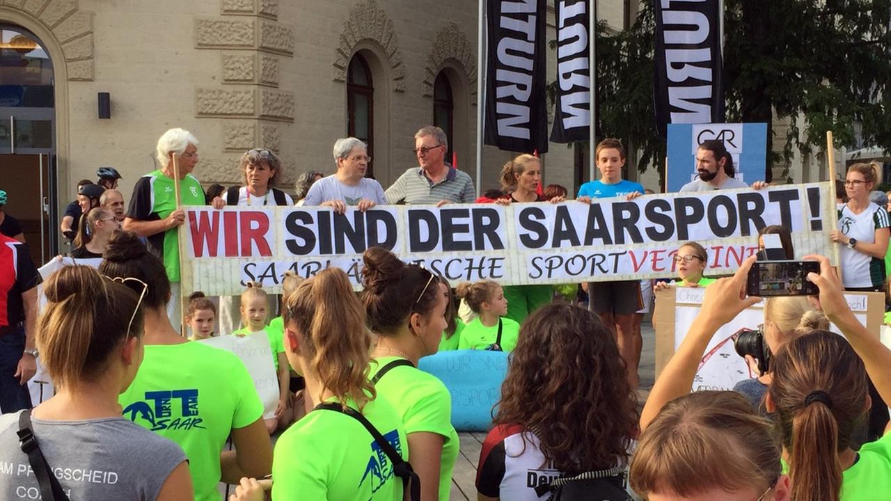 Demonstranten halten in Saarbrücken ein Transparent mit der Aufschrift "Wir sind der Saarsport" in der Hand