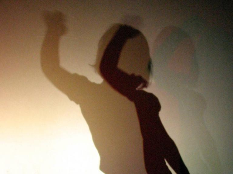 Eine Frau Tanz hinter einem Vorhang, durch den verschiedene Schatten entstehen.