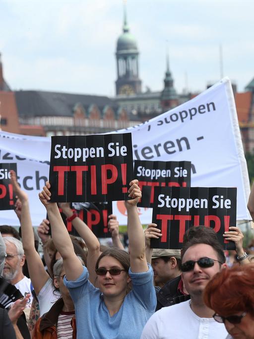 Demonstranten halten bei einer Wahlkampfveranstaltung der CDU auf dem Hamburger Fischmarkt ein Plakat mit der Aufschrift "Stoppen Sie TTIP" in die Höhe.