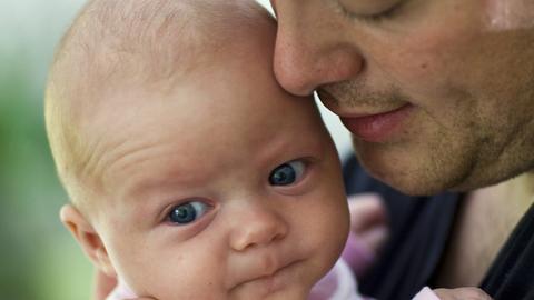 Ein Vater hält seine drei Monate alte Tochter im Arm.