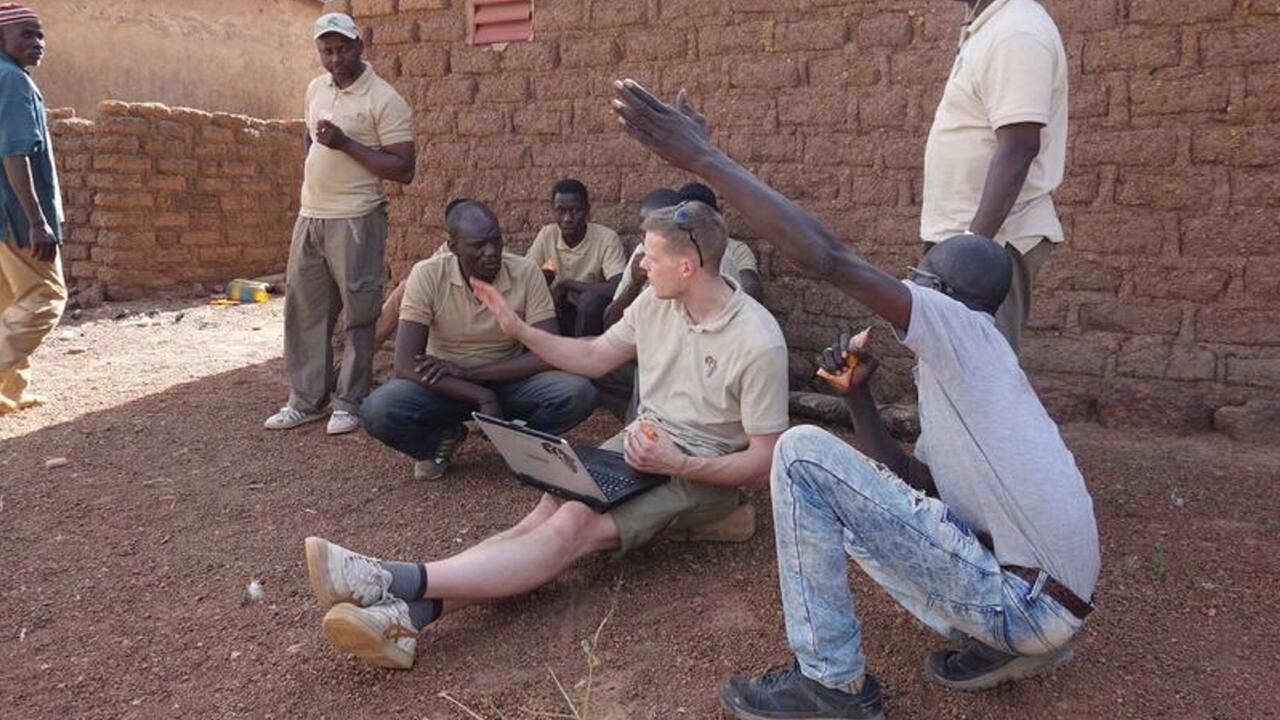 Ein Techniker aus Deutschland und Männer aus der Umgebung sitzen zusamen auf dem Boden und sprechen miteinander. Ein Techniker aus Deutschland und Männer aus der Umgebung sitzen zusamen auf dem Boden und sprechen miteinander.